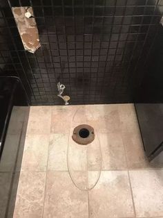 a bathroom with black tiles and a hole in the floor that looks like a drain