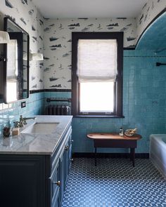 a bathroom with blue and white tile walls, two sinks and a window in the corner