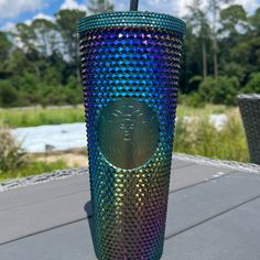 a colorful cup with a straw sticking out of it sitting on a table next to some water