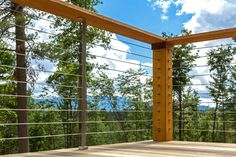 a wooden deck with metal railing and trees in the background