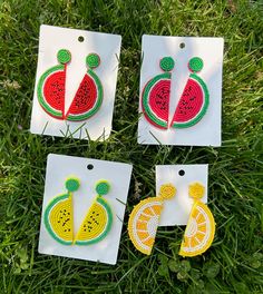 four pieces of crocheted fruit are on the grass with tags attached to them