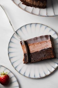 two plates with slices of chocolate cake and a strawberry on the plate next to them