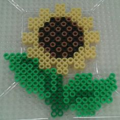 a flower made out of legos sitting on top of a white table next to green and yellow circles