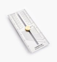 a ruler with a gold disc on it's side, sitting on a white surface