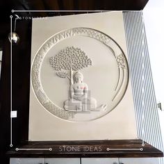 a white plaque with a buddha sitting on top of it