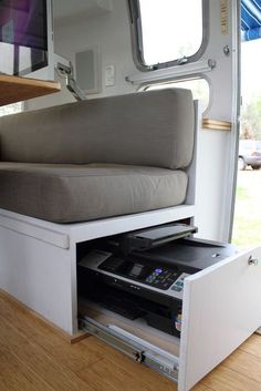 the inside of a camper with its bed pulled out and drawers open to reveal an entertainment center