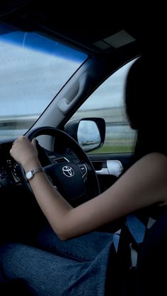 a woman driving a car in the dark with her hands on the steering wheel and looking out the window