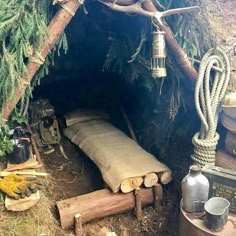 there is a tent made out of logs and rope with a lantern hanging from the ceiling