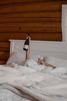 a woman laying in bed holding a bottle of wine