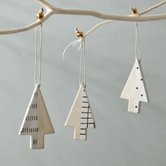 three ornaments hanging from a tree branch with white and black designs on it's sides