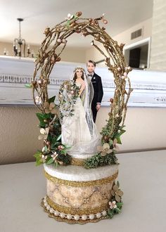 a wedding cake topper with a bride and groom standing in front of an arch