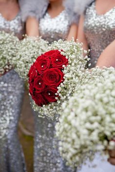 the bridesmaids are holding their bouquets with red roses and baby's breath