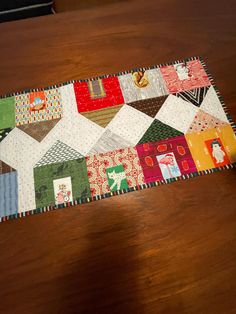 a close up of a patchwork table runner on top of a wooden table next to a cat