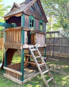 there is a wooden play house with a slide and ladder to the top, in the yard