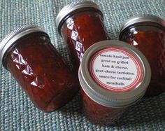 three jars filled with jam sitting on top of a blue tablecloth covered floor next to each other