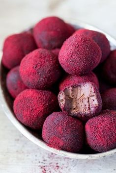 a metal bowl filled with red fruit on top of a table