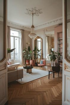 a living room filled with lots of furniture and plants on top of a hard wood floor