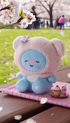 a small stuffed animal sitting on top of a pink mat next to a cupcake