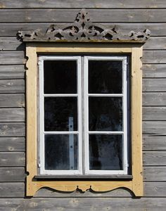 an old window on the side of a wooden building with white trim and yellow frame