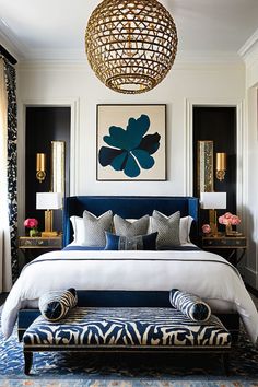 a bedroom with blue and white bedding, gold accents and artwork on the wall