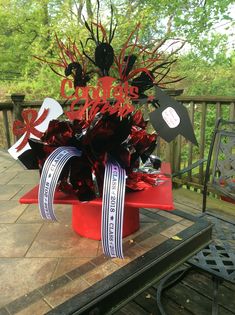 a red hat with black and white decorations on it sitting on a table in front of a deck