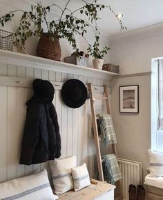 a coat rack with hats on top of it next to a bench and potted plant