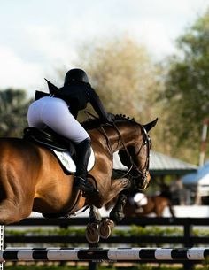 a woman riding on the back of a brown horse while jumping over an obstacle with it's legs in the air