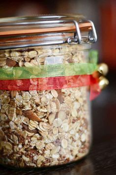 a jar filled with granola sitting on top of a wooden table next to a red ribbon