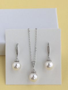 This classic pearl bridal jewelry set includes#Cubic zirconia and pearl bridal earrings in rhodium plated brass setting. Earrings feature 10mm Swarovski pearl drop that dangles from crystal encrusted ear wire. Total length of the earrings is 3 cms .#Classic pearl bridal necklace and pendant set with rhodium plated brass peg and bail. Necklace features a pendant with 10mm Swarovski single pearl drop that dangles from rhodium plated brass peg and cubic zirconia bail. Length of the rhodium plated c Silver Pearl Pendant Earrings For Wedding, Classic Wedding Jewelry Sets With Matching Earrings, Classic White Jewelry Sets For Wedding, Sterling Silver Pearl Earrings With Pendant For Wedding, Silver Jewelry Sets With Pearl Drop For Formal Occasions, Elegant Pearl Necklace With Matching Earrings For Wedding, Classic Silver Jewelry Sets With Pearl Drop, Anniversary Jewelry Sets With Pearl Drop And Cubic Zirconia, Classic Bridal Earrings With Pearl Pendant For Wedding