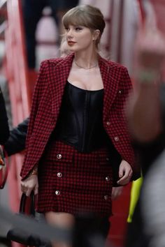 taylor swift is seen walking down the street wearing a red and black jacket with buttons