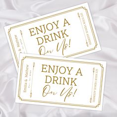 two tickets with the words enjoy a drink and enjoy a drink on it in gold foil