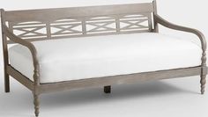 a wooden bench with white pillows on it's back and seat cushions, in front of a gray background