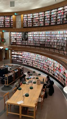 a library filled with lots of books and people sitting at tables in front of them