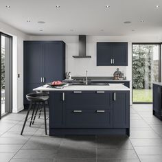 a large kitchen with blue cabinets and counter tops, along with black bar stools