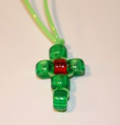 a green necklace with a red and green bead hanging from it's end