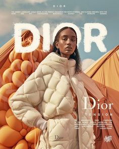 a woman in a puffy jacket standing next to an orange and white tent with the word dior on it