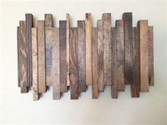 a wooden wall hanging on the side of a white wall with wood planks attached to it