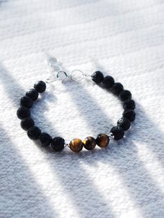 This Tigers Eye and Lava bracelet is sure to become an everyday staple. Tigers eye promotes inner strength and was once considered more precious than gold. Part of our Men's Collection, but designed to be gender inclusive, this unique bracelet is a classic staple.✦ DETAILS ✦✧ Name: Ekewaka (eh-keh-WAH-kah) - The protector or guardian of riches or wealth.✧ Genuine Tigers Eye beads .✧ 8mm Lava Beads.✧ Sterling silver components.✧ All Ke Aloha Jewelry pieces come packaged thoughtfully, beautifully, Everyday Spiritual Bangle Bracelet, Everyday Spiritual Sterling Silver Bracelets, Minimalist 8mm Bead Bracelet Jewelry, Everyday Symbolic Bracelets, Minimalist 8mm Bead Bracelet, Spiritual 8mm Beads Jewelry For Everyday, Minimalist Bracelets With 8mm Beads For Healing, Sterling Silver Spiritual Bracelet For Meditation, Minimalist Gemstone Beads Bracelets For Meditation