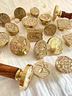 a bunch of different types of buttons on a white table cloth with a wooden handle