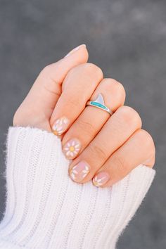 a woman's hand wearing a ring with flowers on it