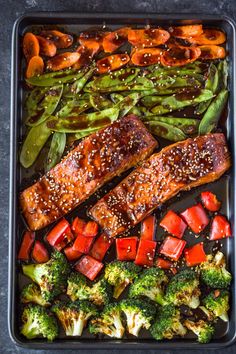 salmon, broccoli and carrots in a pan with sesame seeds on the side