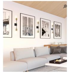 a living room filled with white furniture and pictures on the wall above it's coffee table