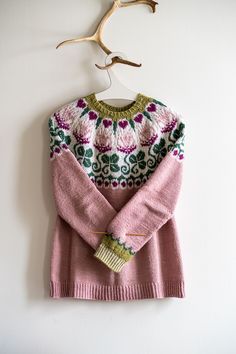 a pink sweater hanging on a wooden hanger