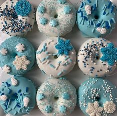 there are many frosted doughnuts in the box on the table and one is decorated with snowflakes