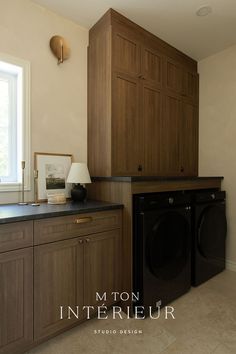 a washer and dryer are in the middle of a room with wood cabinets