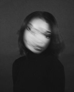 a black and white photo of a woman's face with her hair blowing in the wind