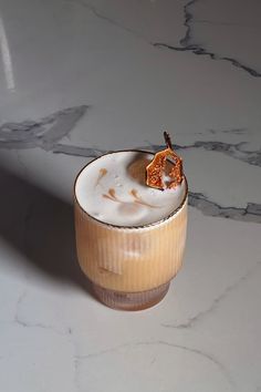 a glass with some kind of drink in it on a counter top next to a marble floor