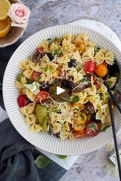 a white bowl filled with pasta salad next to two bowls of oranges and other food