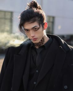 a young man with black hair and piercings on his neck wearing a black coat