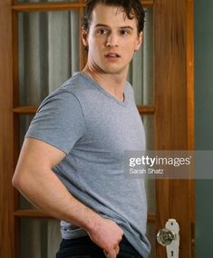 a young man standing in front of a door with his hands on his hips and looking at the camera